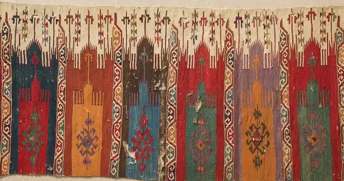 A flatweave of six tall niche panels in red, blue, green, orange and violet, with worn patches and small holes, laid on plain linen